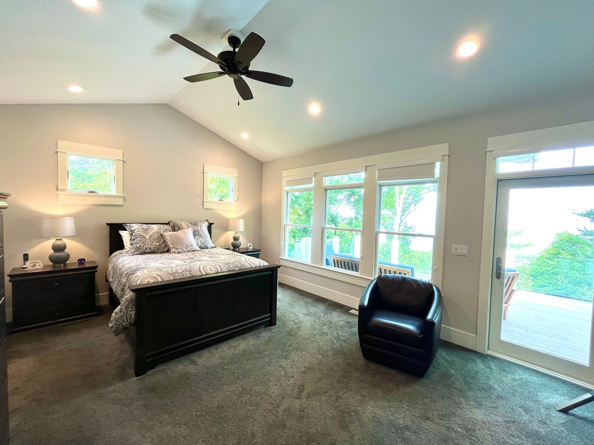 A bedroom with a bed , chair , nightstand and ceiling fan.