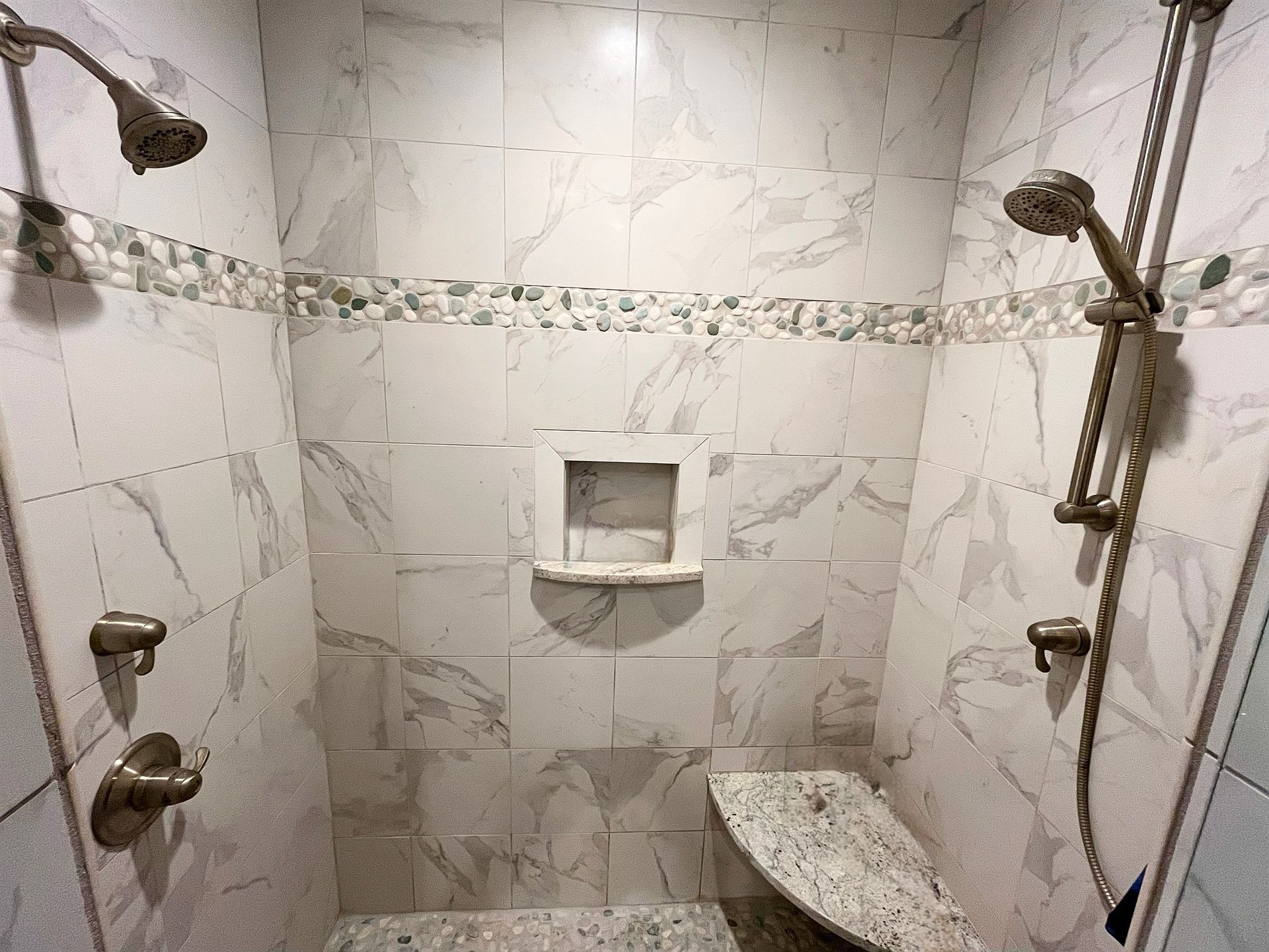 A bathroom with two showers and a bench.