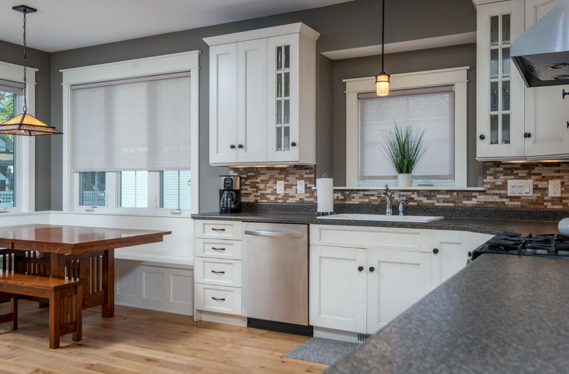 A kitchen with white cabinets and a wooden table and bench.