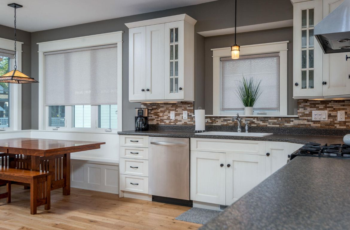 A kitchen with white cabinets and a wooden table and bench.