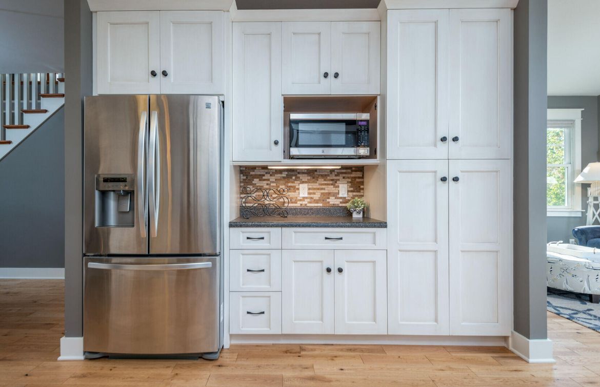 A kitchen with white cabinets and a stainless steel refrigerator.