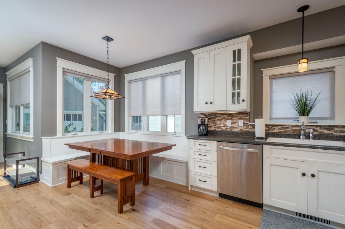 A kitchen with a table , benches , and stainless steel appliances.