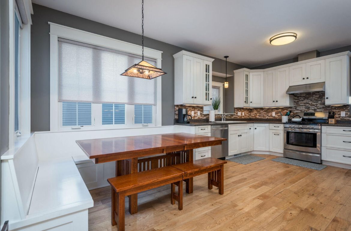 A kitchen with a table and benches in it.