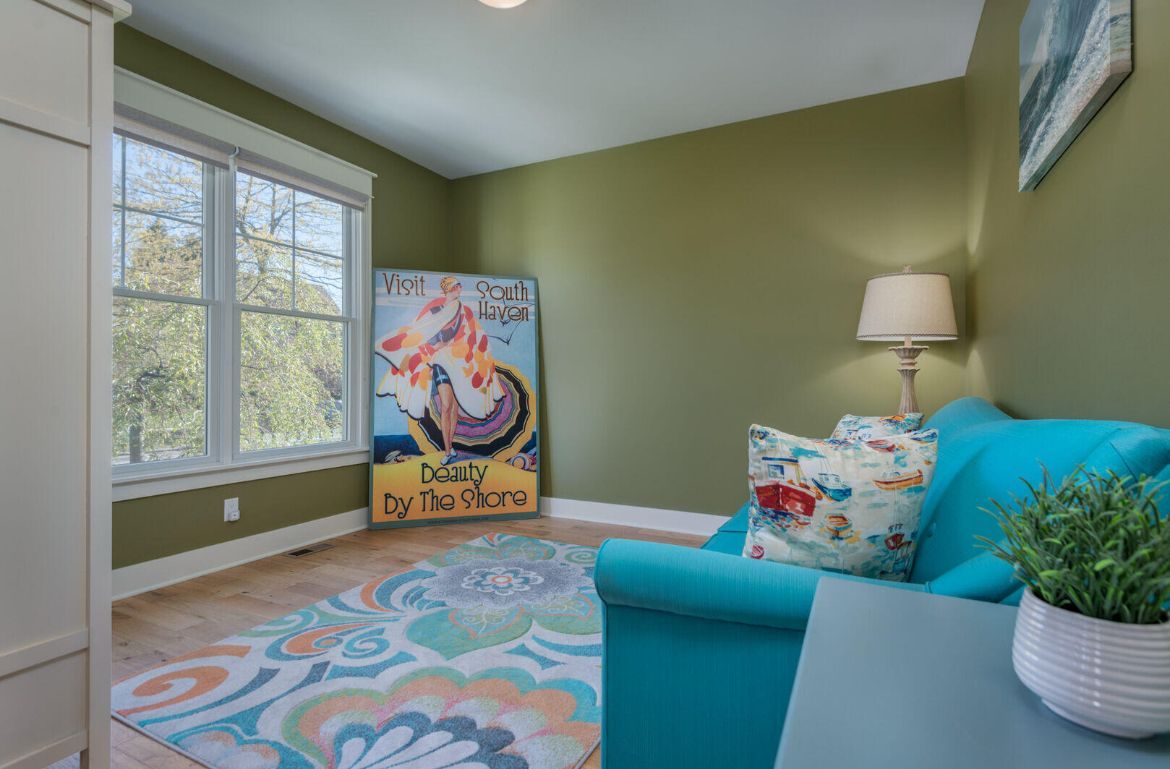 A living room with a blue couch and a rug.