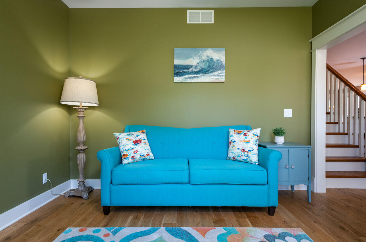 A living room with green walls and a blue couch.