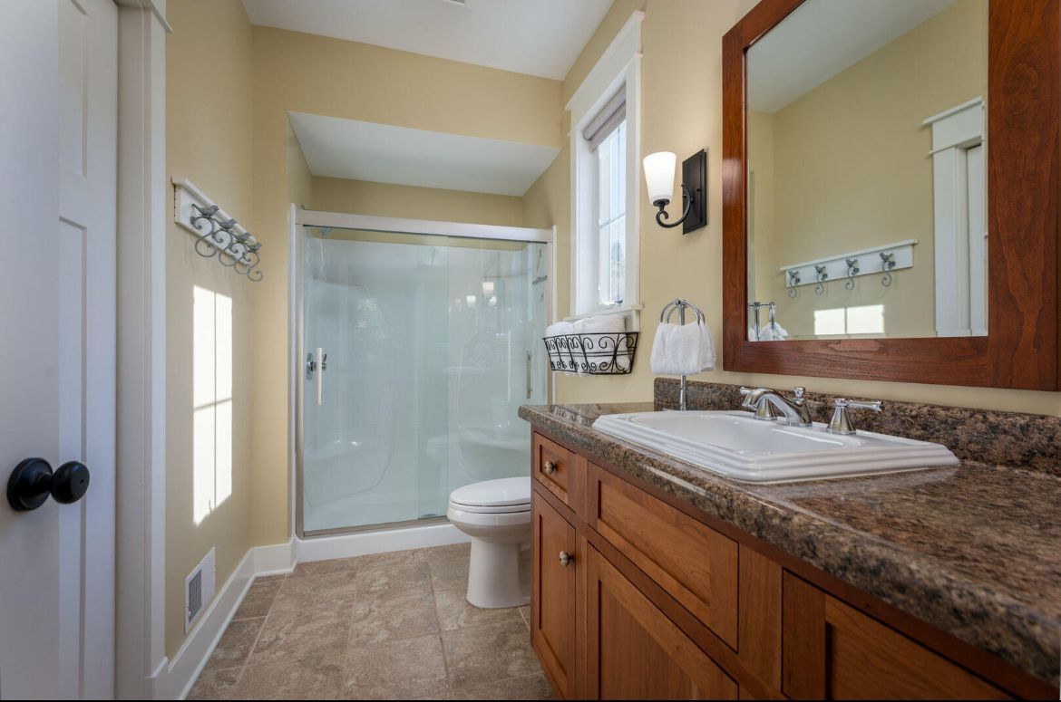 A bathroom with a sink , toilet , shower and mirror.