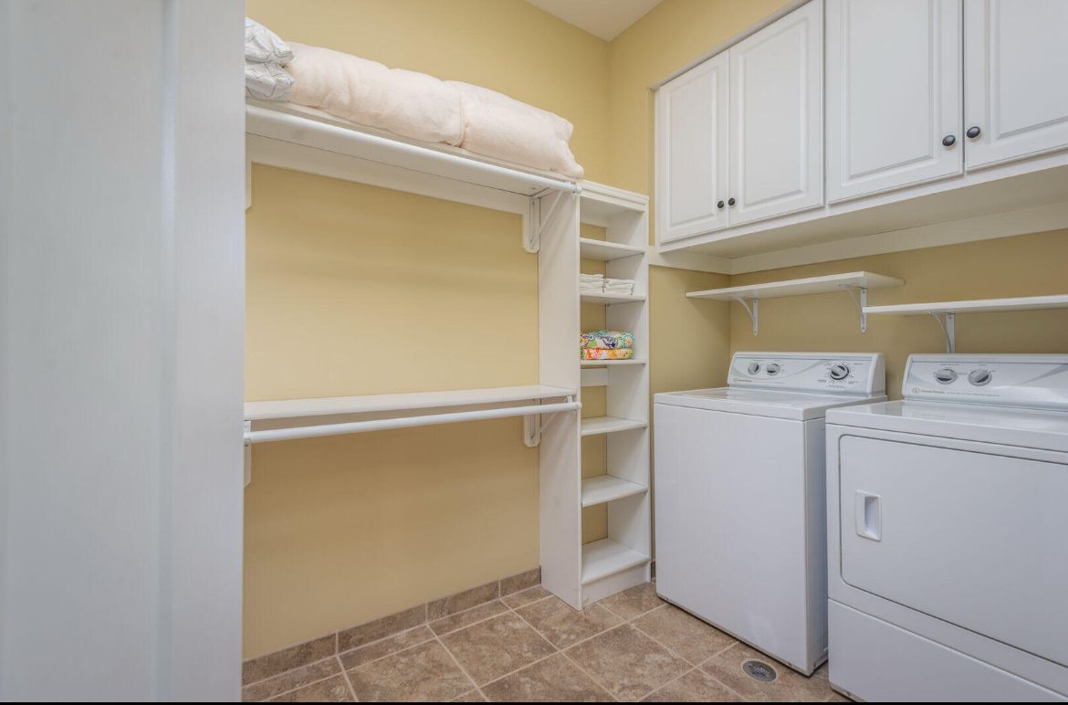 A laundry room with a washer and dryer and shelves.