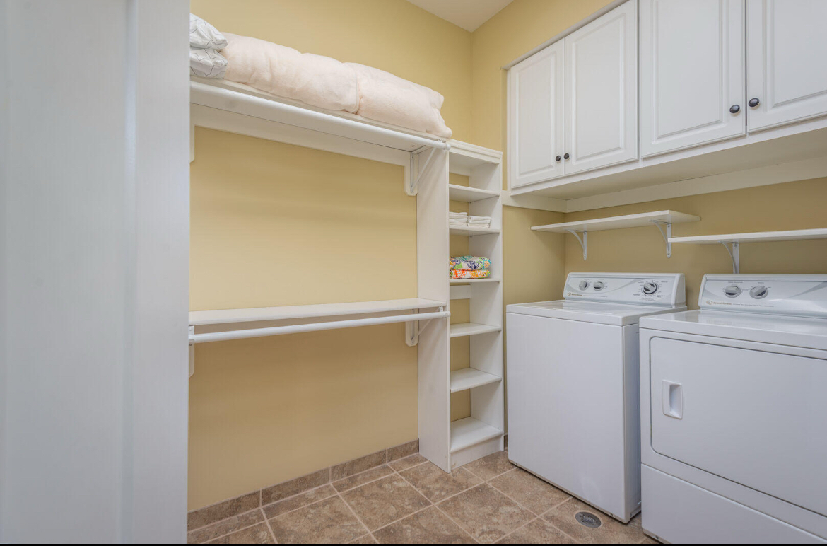 Laundry room with washer and dryer, white cabinets, open shelves, and a tiled floor.