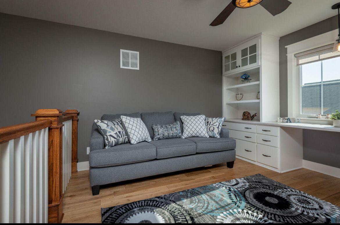 A living room with a couch and a rug and a ceiling fan