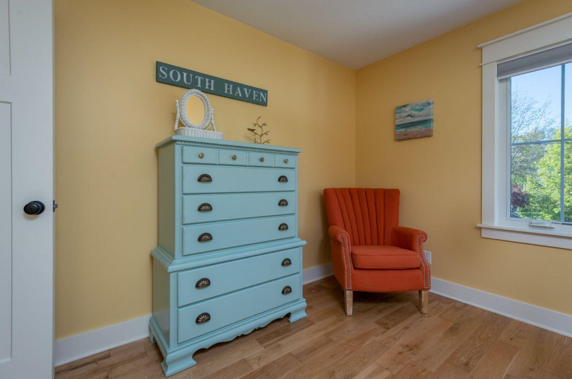 There is a dresser and a chair in the room.