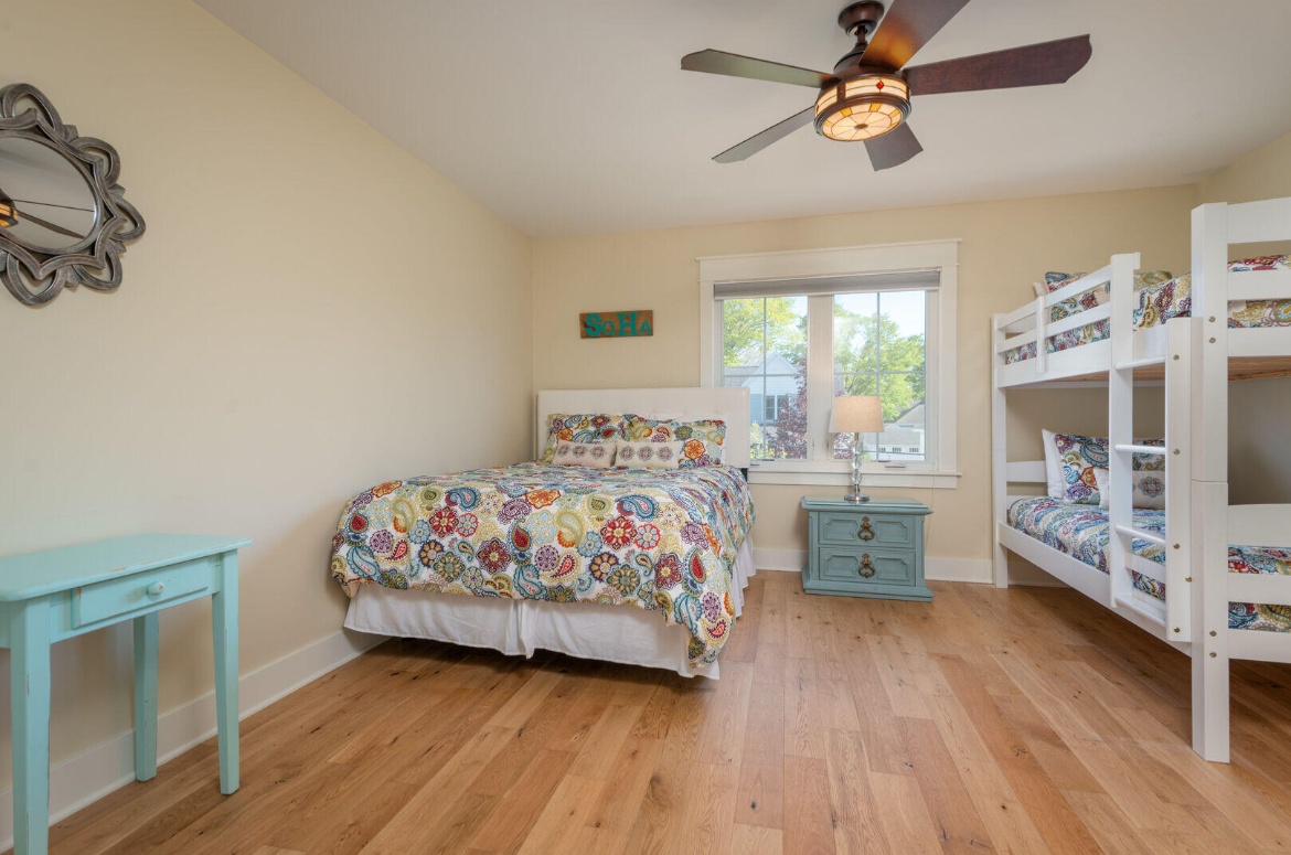 A bedroom with two bunk beds and a ceiling fan.