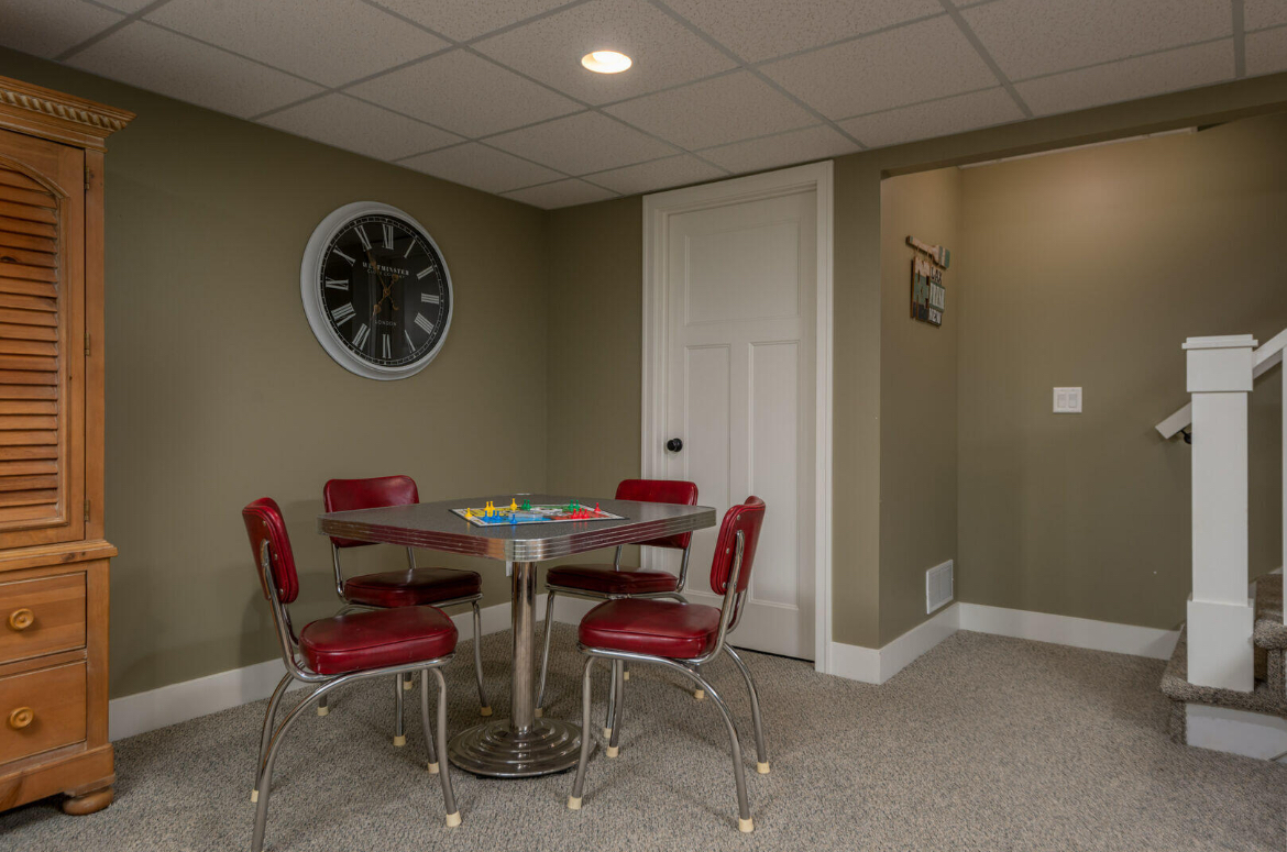 A game room with a table and chairs and a clock on the wall.