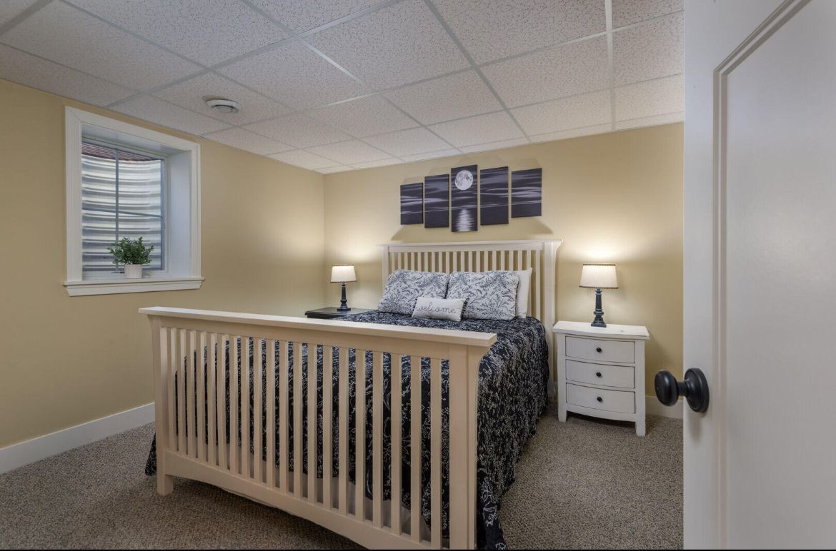 A bedroom with a bed , nightstands , and a window.