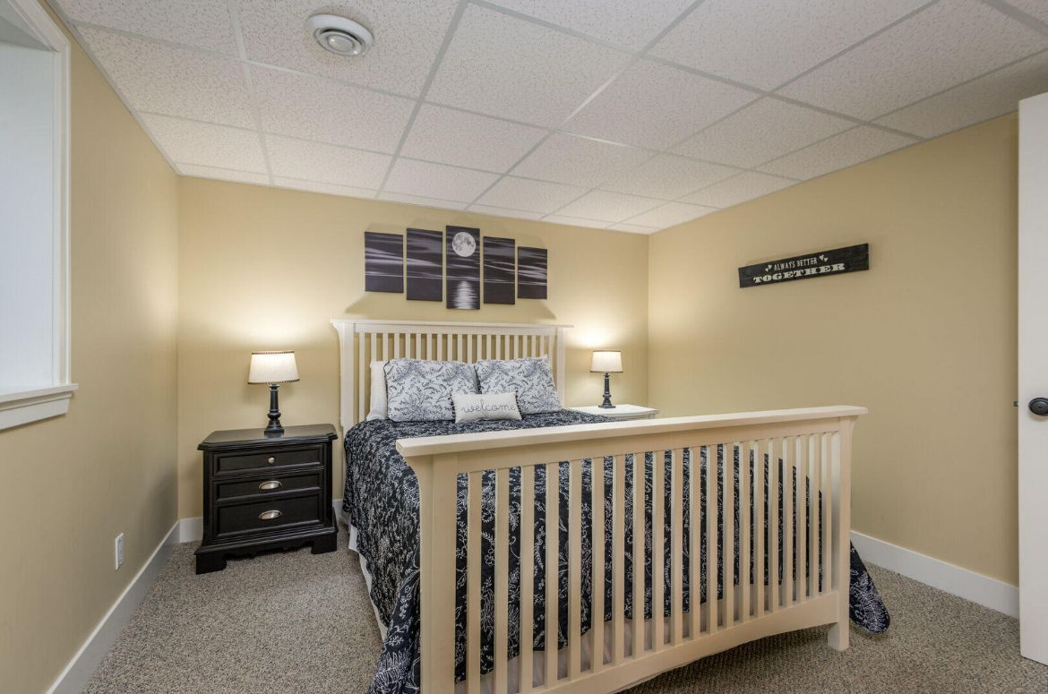 A bedroom with a bed , nightstand , lamps and a window.
