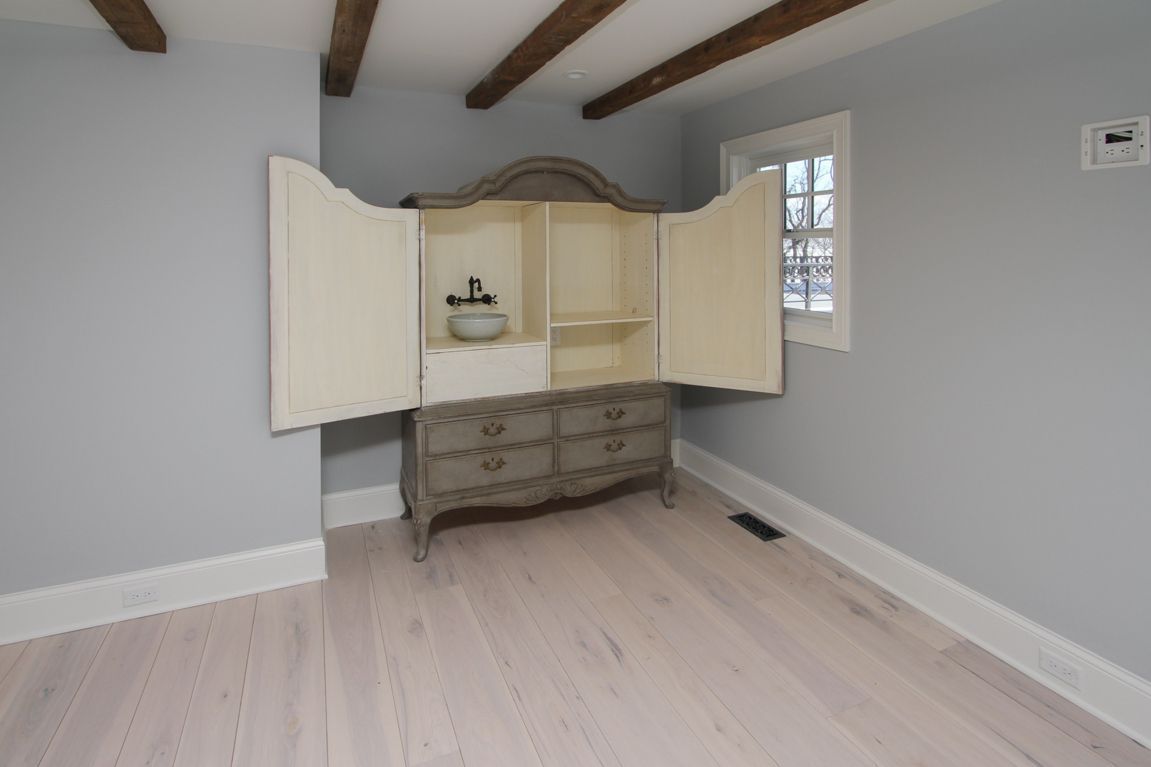 An empty room with a dresser and a window.