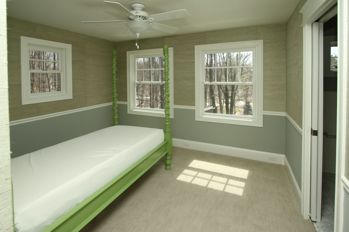 A bedroom with a green canopy bed and a ceiling fan
