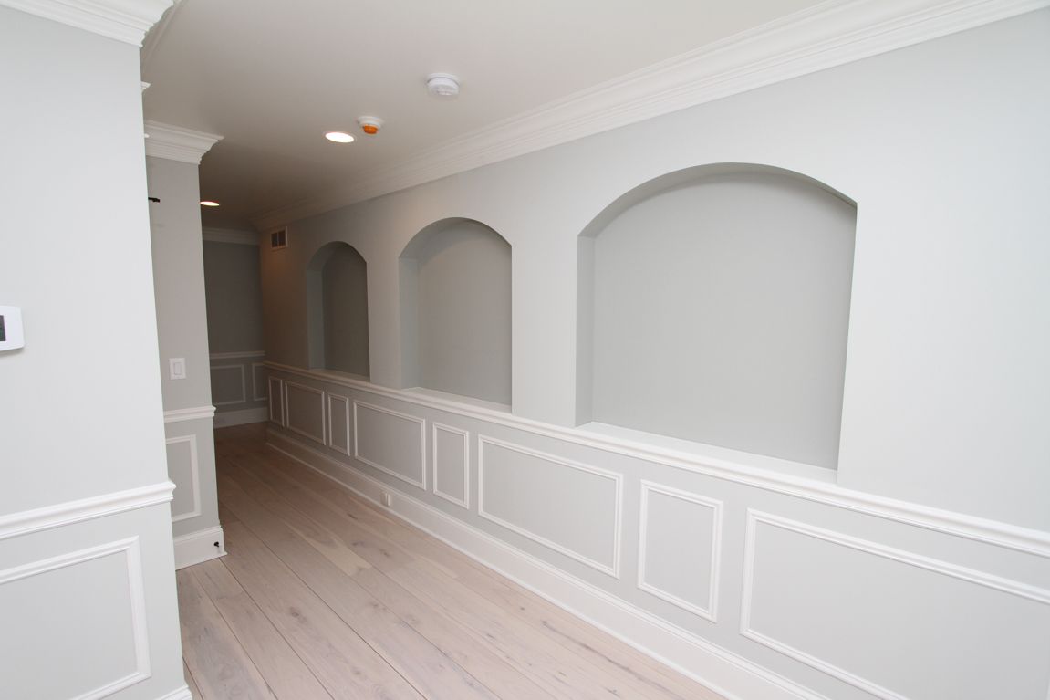 A hallway with white trim and arches on the walls