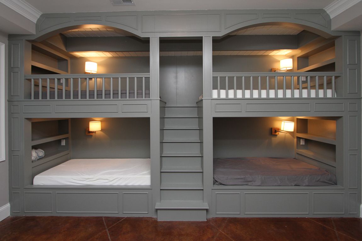A room with three bunk beds and stairs.
