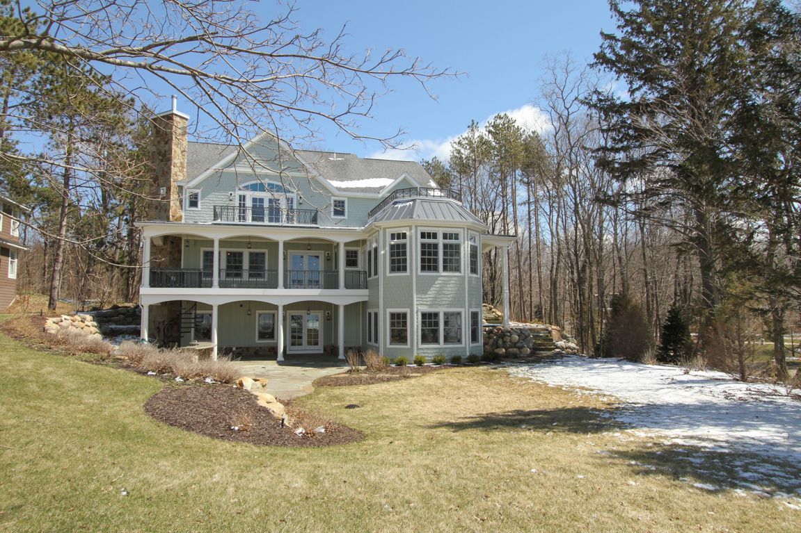 A large house with a lot of windows is surrounded by snow and trees
