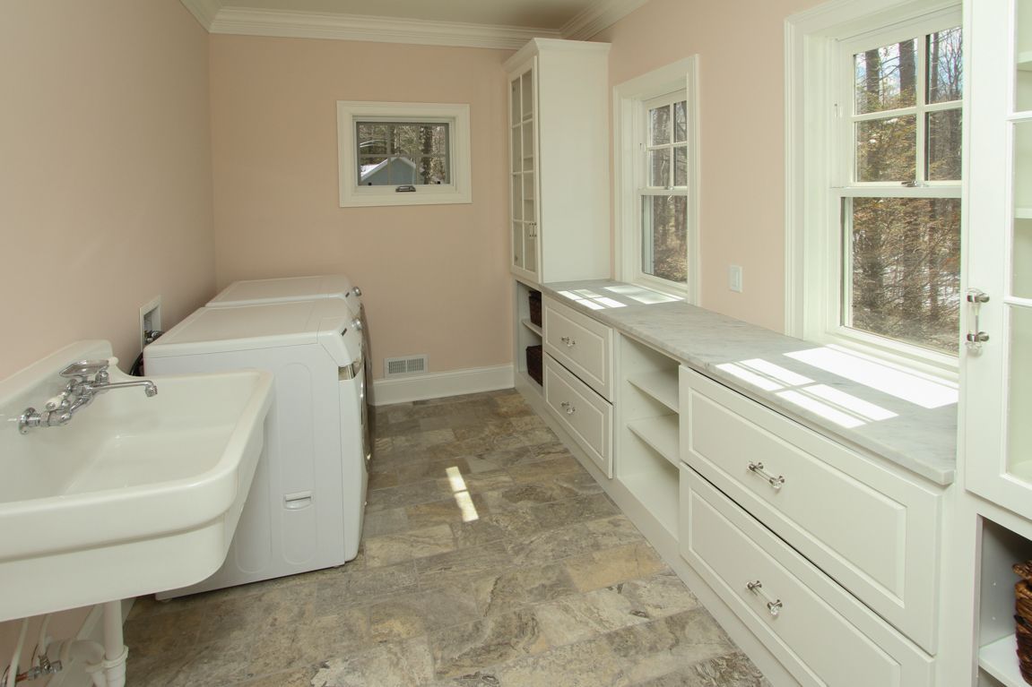 A laundry room with a sink , washer and dryer , and a window.