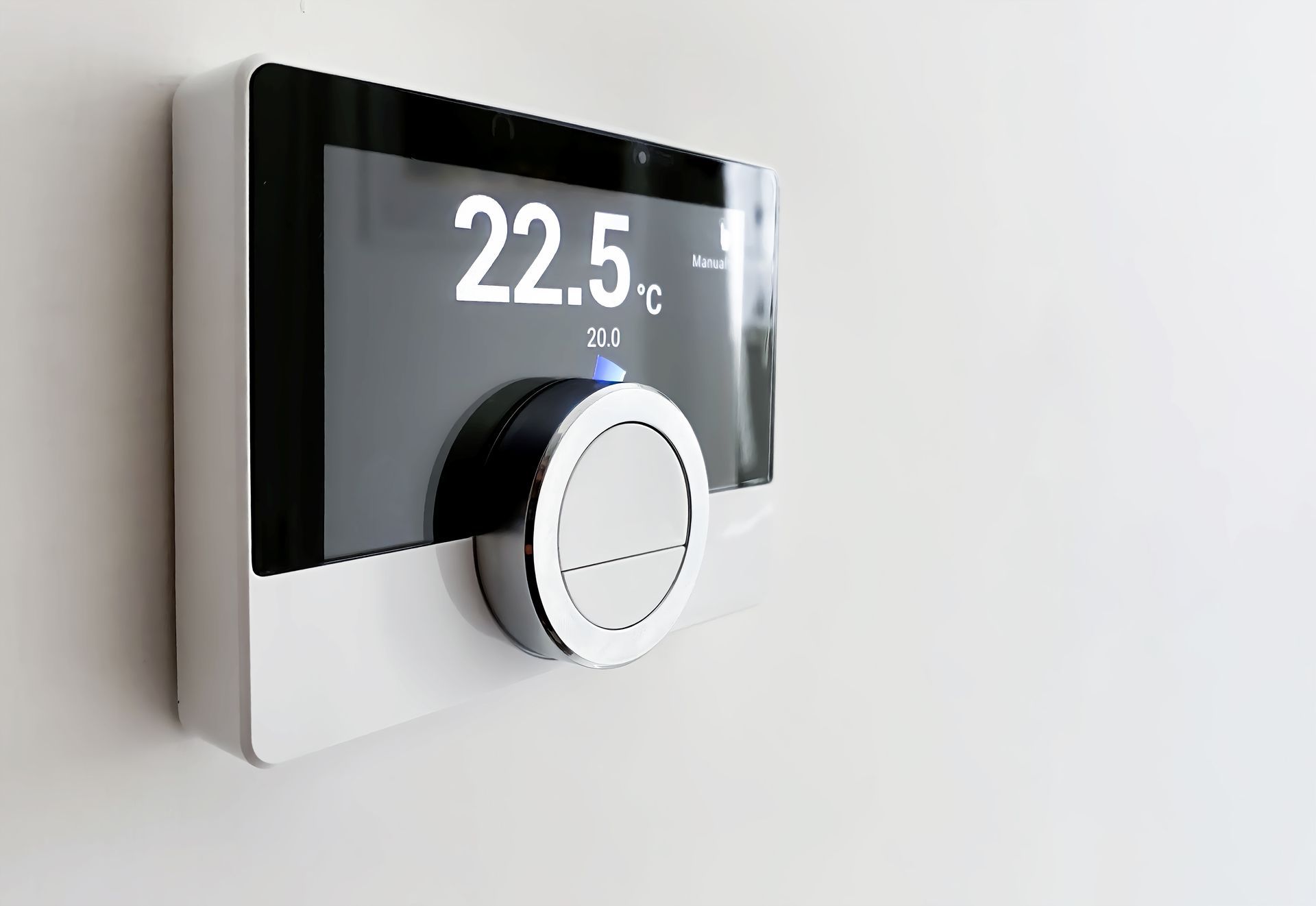 Smart thermostat on a white wall, displaying 22.5°C, with a dial for temperature control.