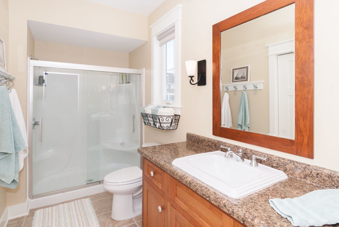 A bathroom with a sink , toilet , shower and mirror.