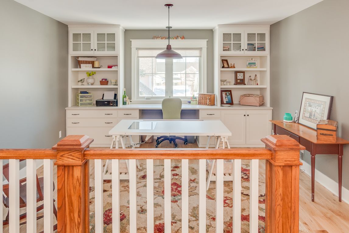 A room with a desk , shelves , and a window.
