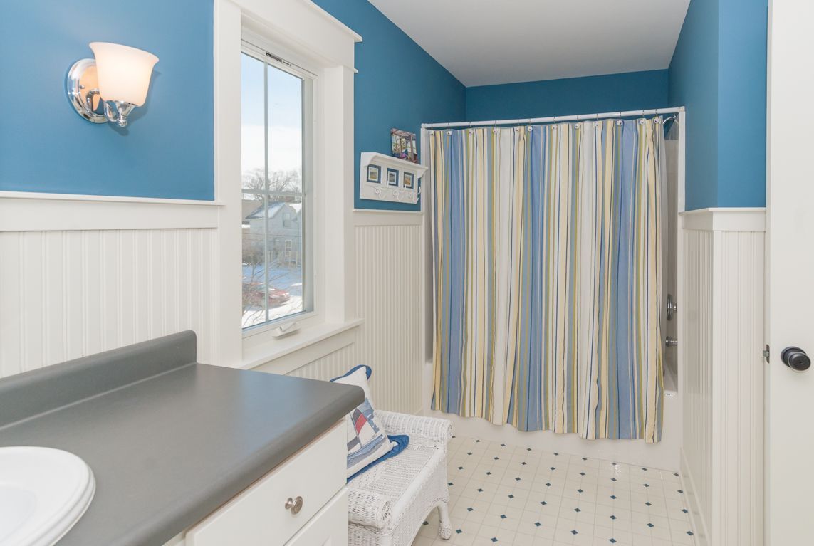 A bathroom with blue walls and a striped shower curtain.