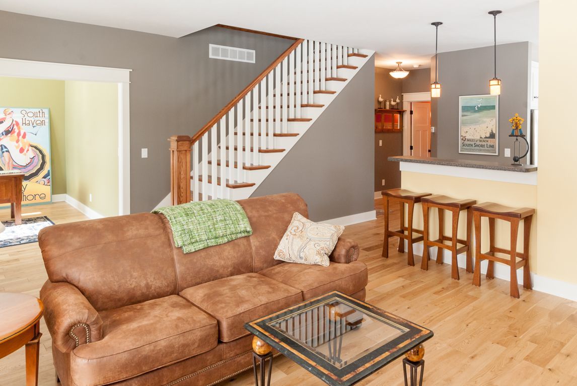 A living room with a brown couch , coffee table and stairs.