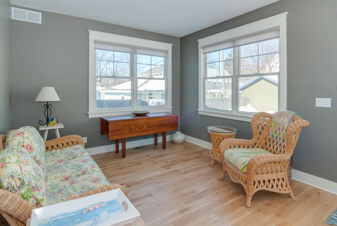 A living room with a couch , chair , table and two windows.