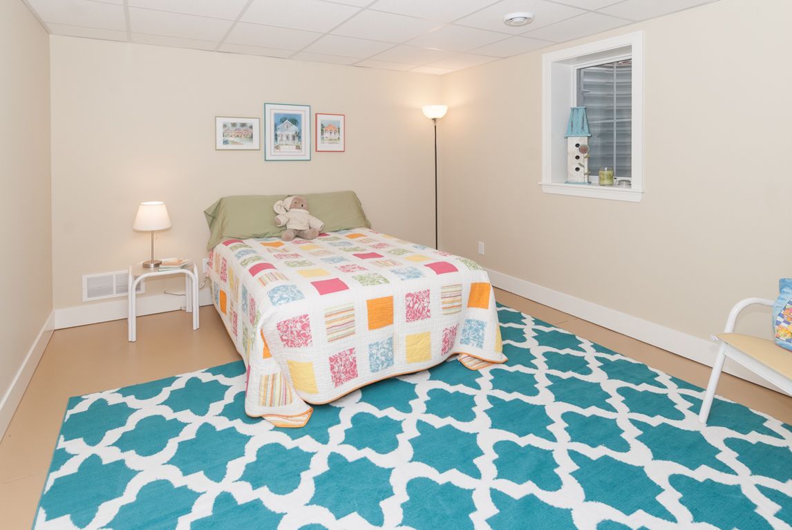 A bedroom with a bed , rug , lamp and window.