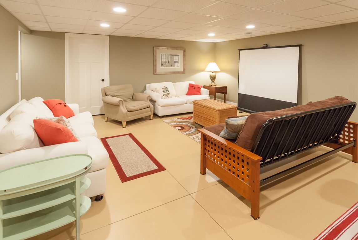 A living room with a couch , chairs and a projector screen.