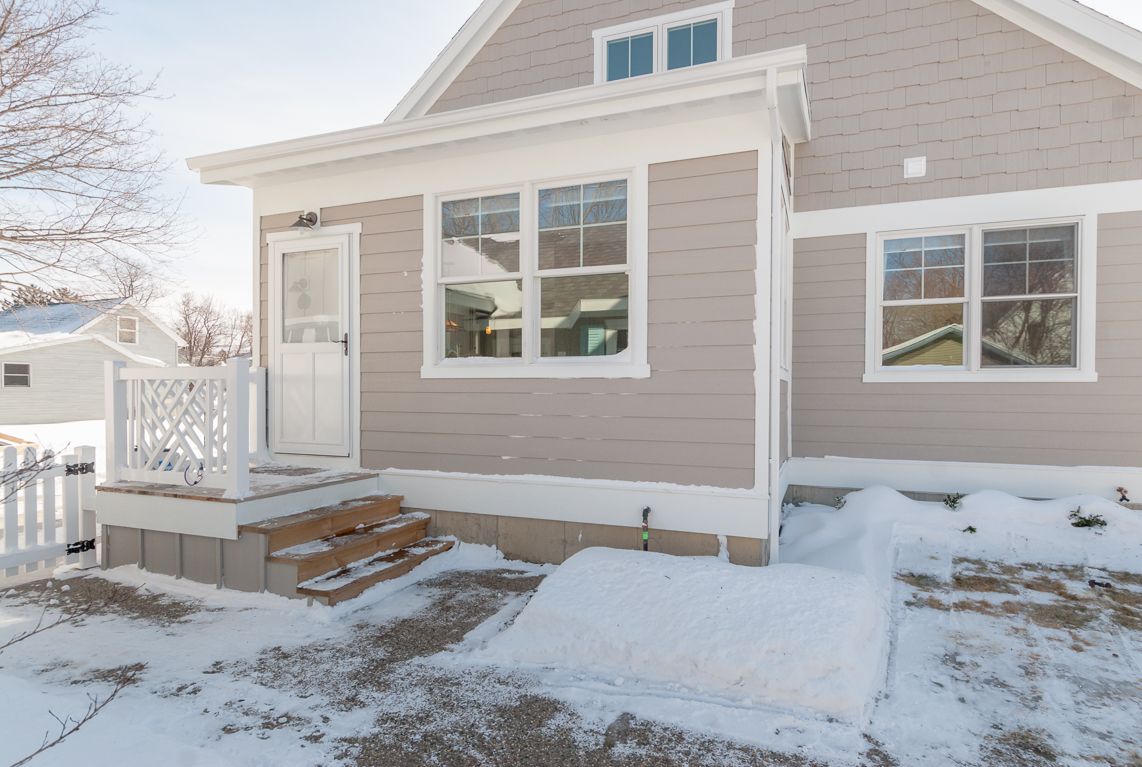 A house with a porch and stairs is covered in snow.