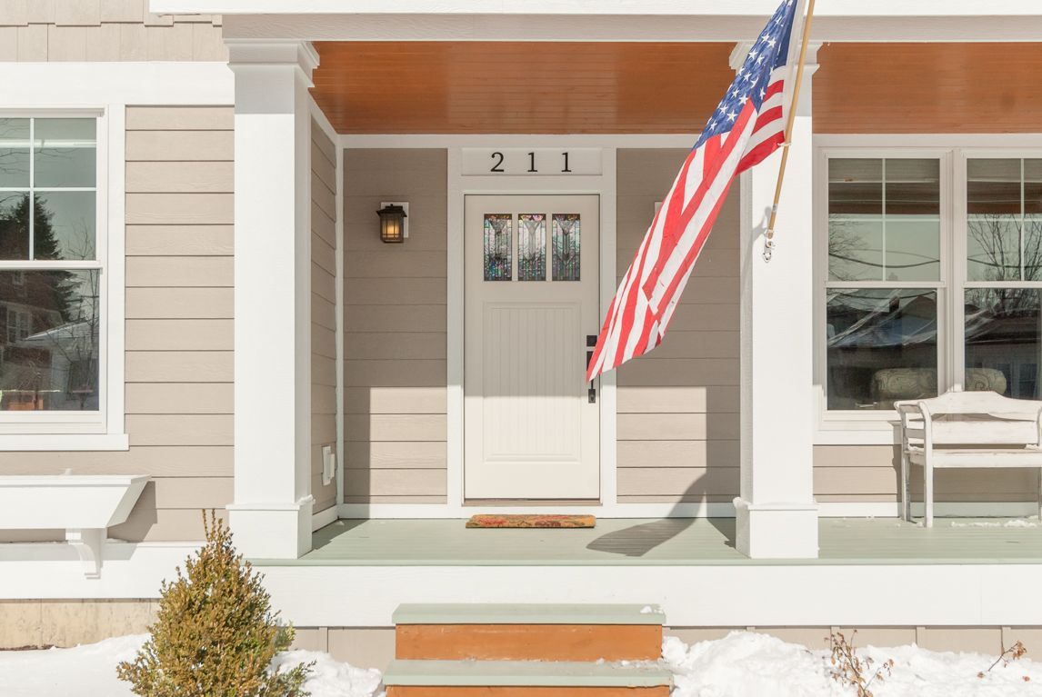 An american flag is flying on the porch of a house.