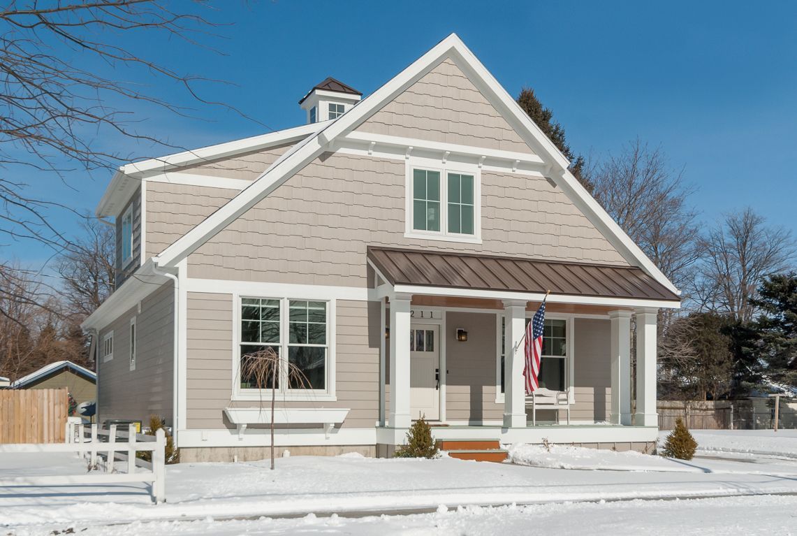 A house with a porch and an american flag in the snow.
