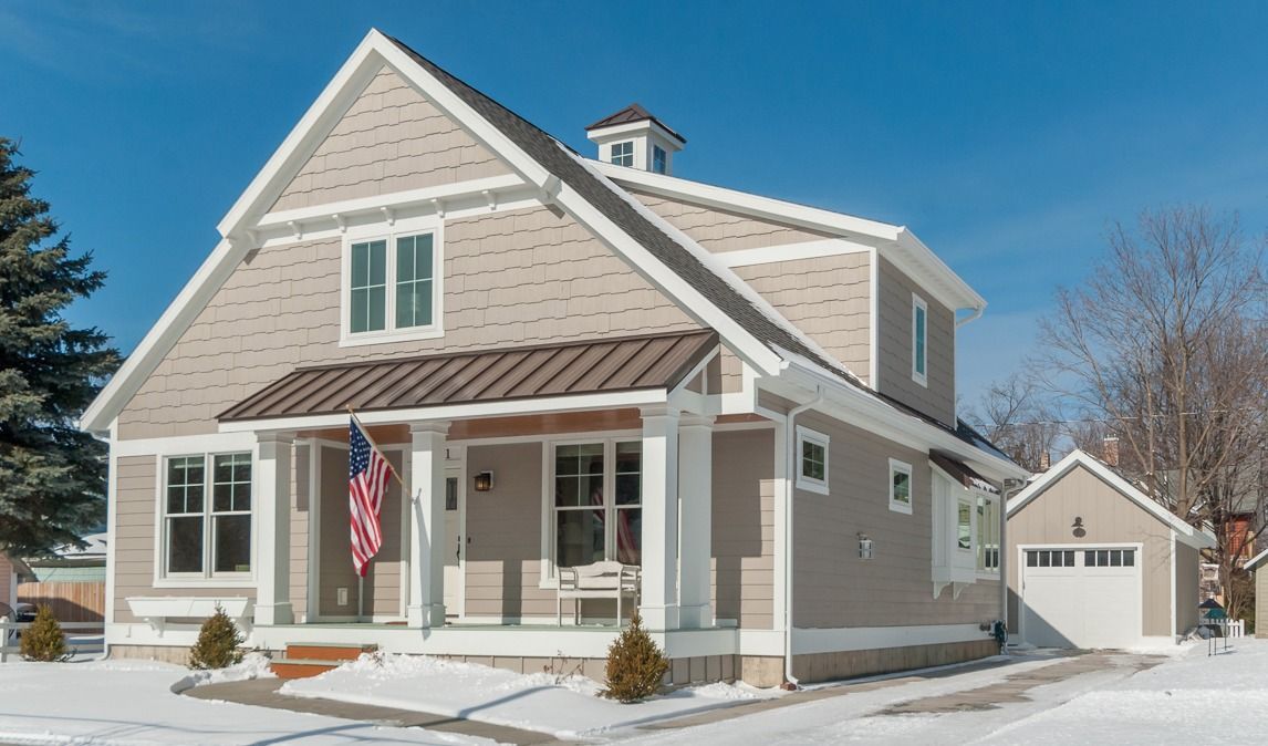 A house with a porch and a garage is covered in snow.