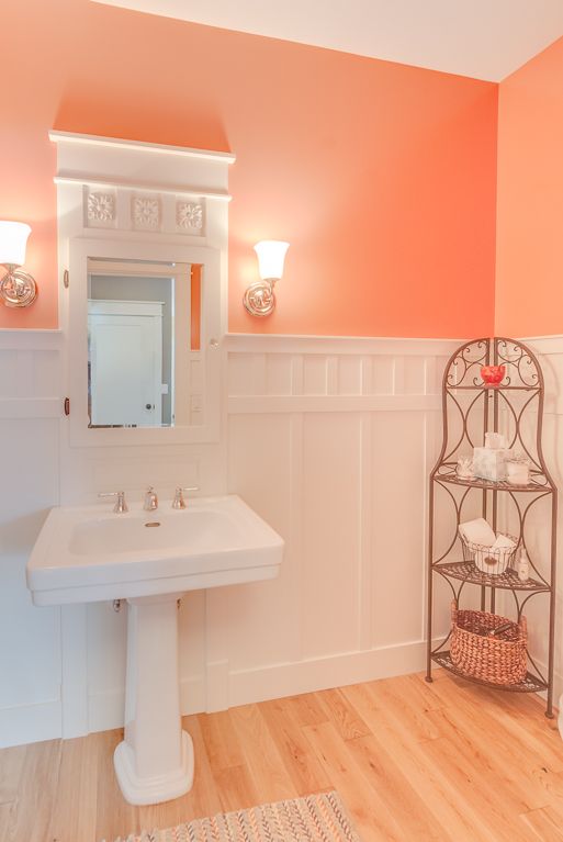 A bathroom with coral walls and a pedestal sink