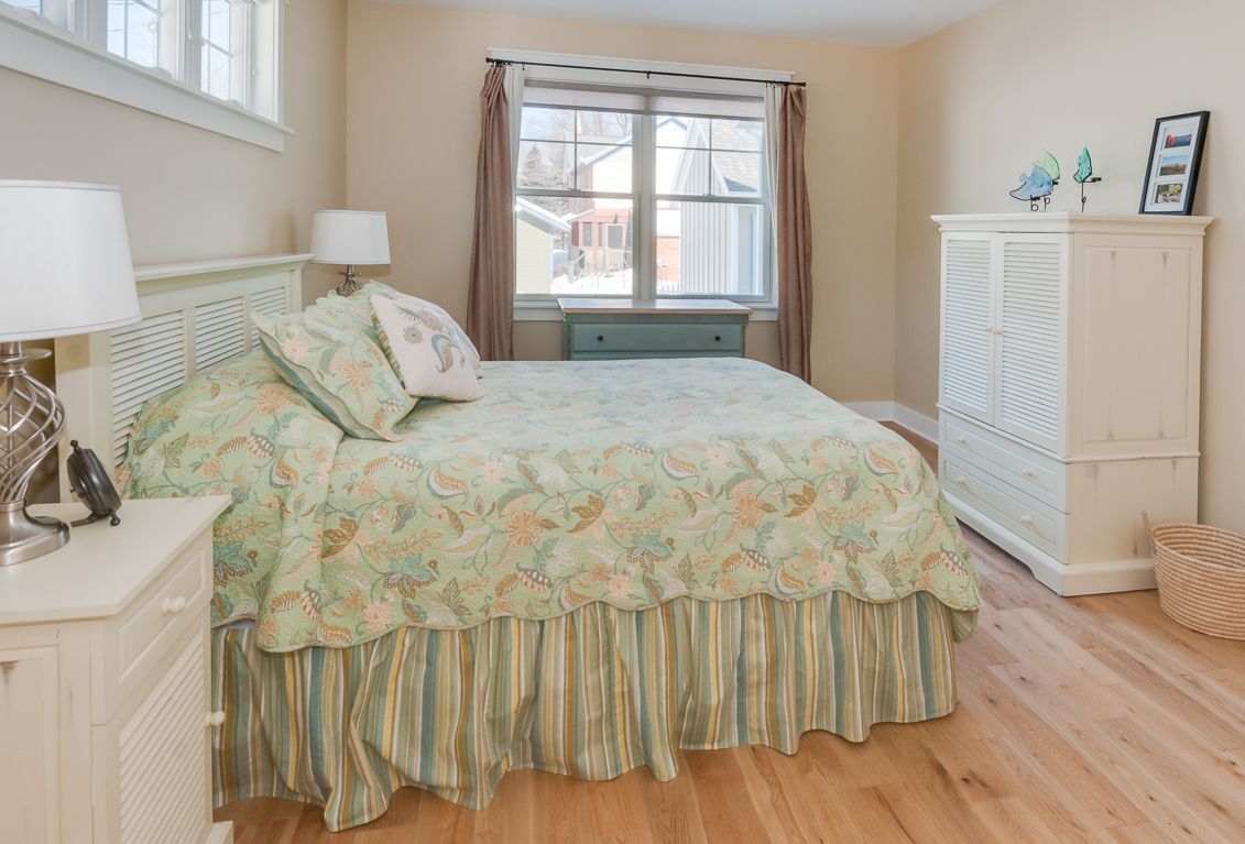 A bedroom with a bed , nightstand , dresser and window.
