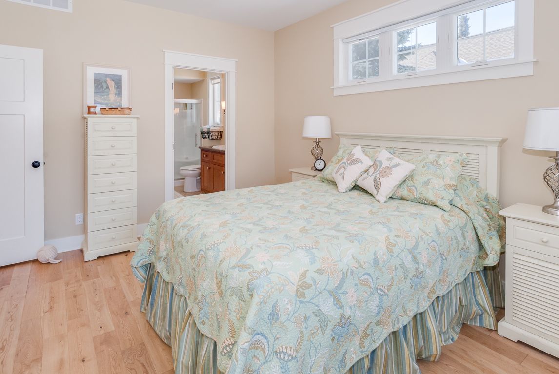 A bedroom with a bed , nightstand , dresser and window.