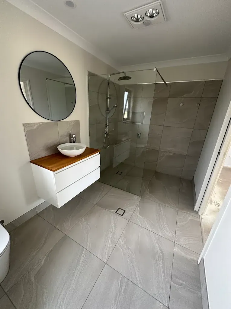 Luxurious gray marble bathroom with bathtub, double vanity, and walk-in shower.