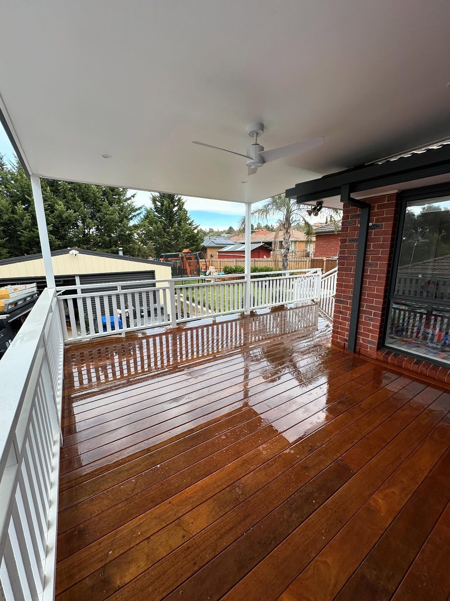 Outdoor patio with a dining table, bench, and decorative fence, leading to an open kitchen, on a sunny day.