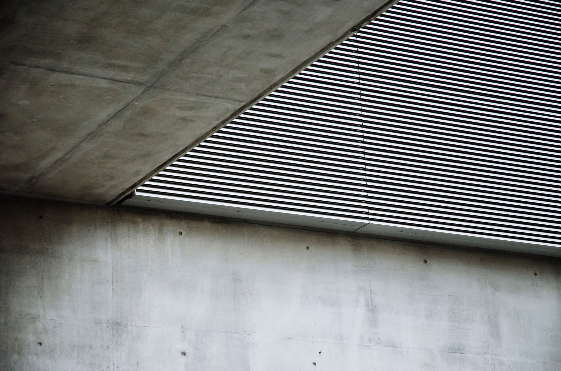 Concrete architecture with angled metal grating, casting shadows.