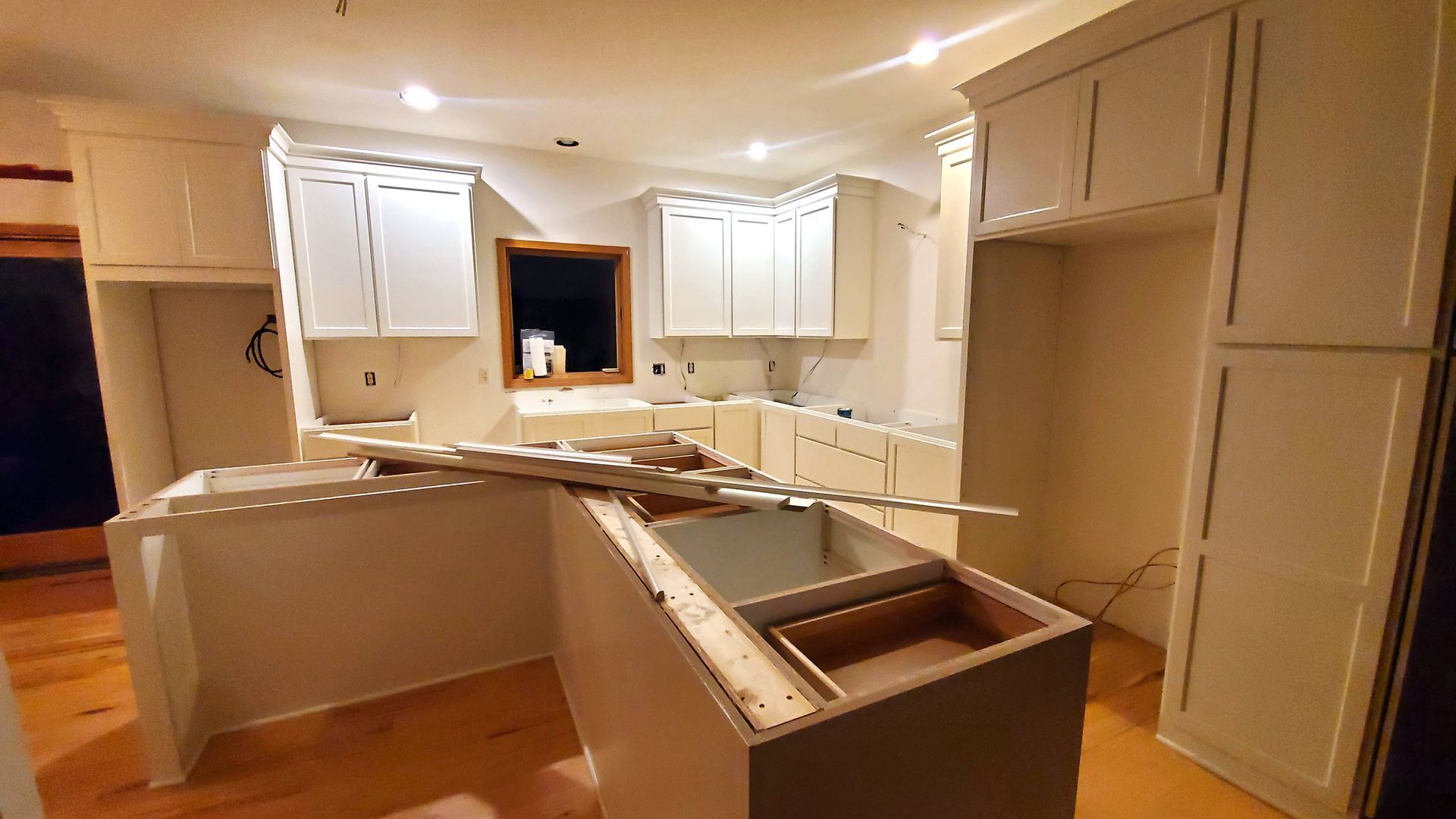 Kitchen under renovation with white cabinets and unfinished island.