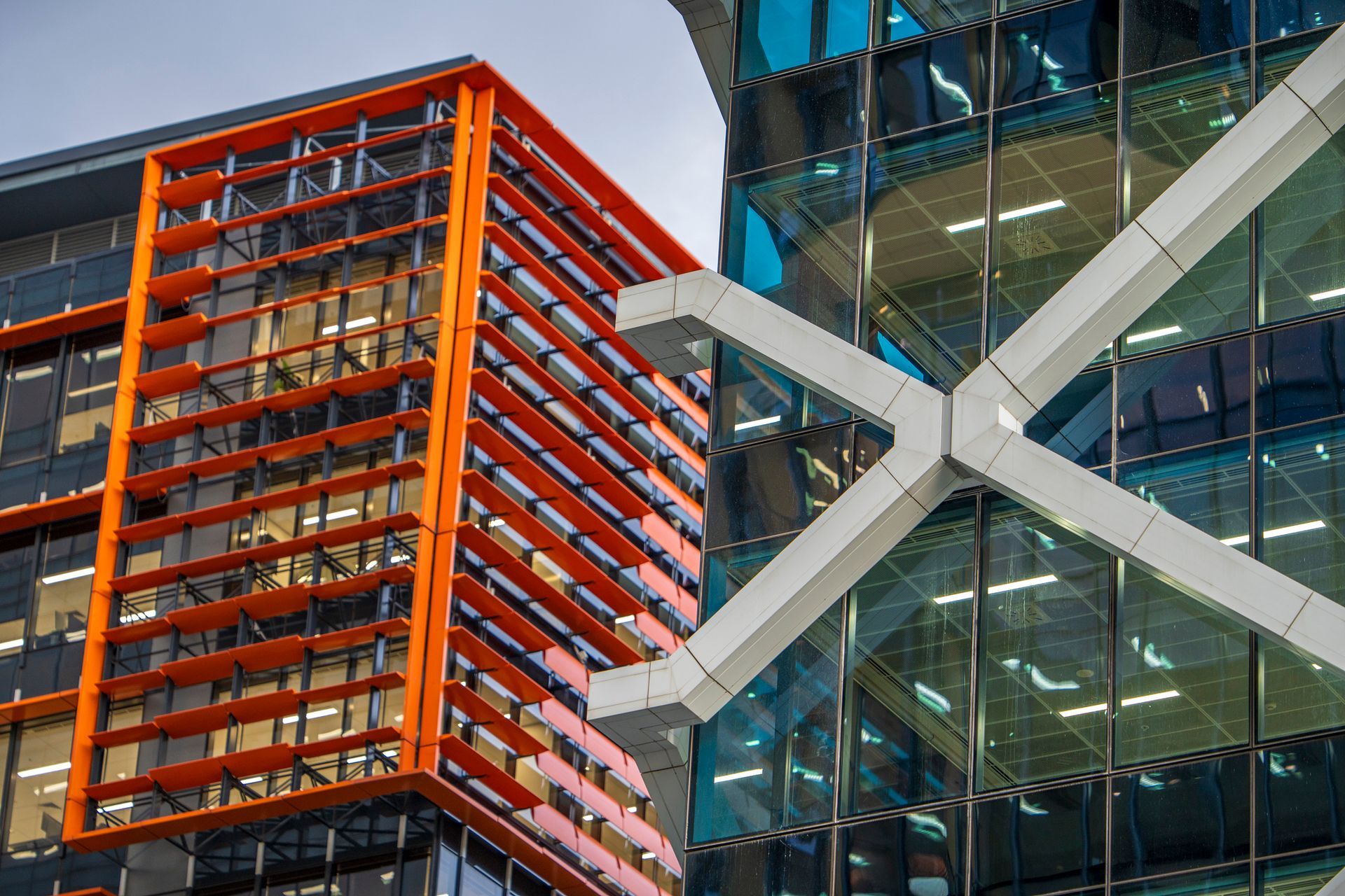 Modern office buildings with orange and blue glass facades, white architectural supports.