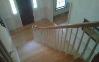 Wooden staircase with white railing leads down, view from above.
