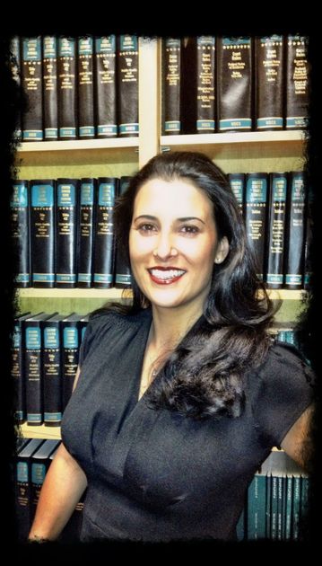 A woman is standing in front of a bookshelf with a book titled 