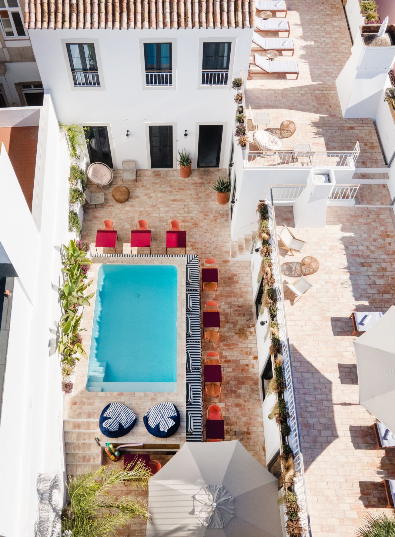 an aerial view of a swimming pool surrounded by chairs and umbrellas