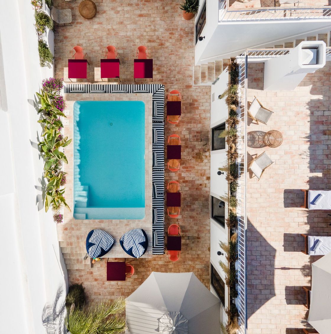 an aerial view of a swimming pool surrounded by chairs and umbrellas