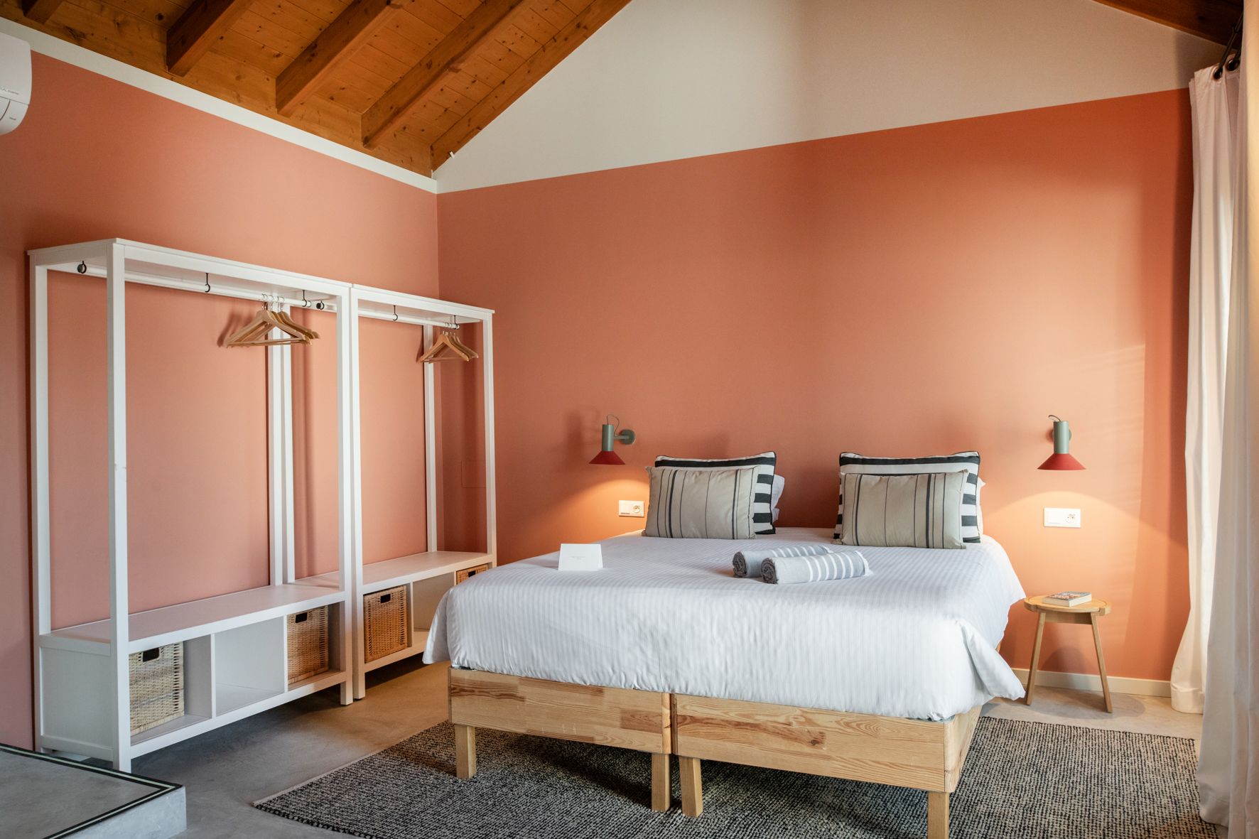 A bedroom with two beds , a closet and a wooden ceiling.