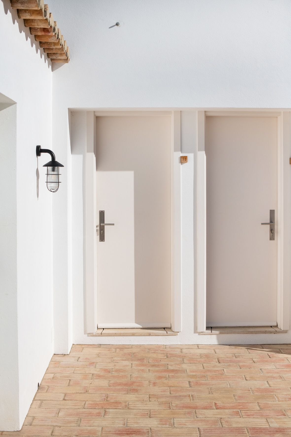 a hallway with two white doors and a brick floor